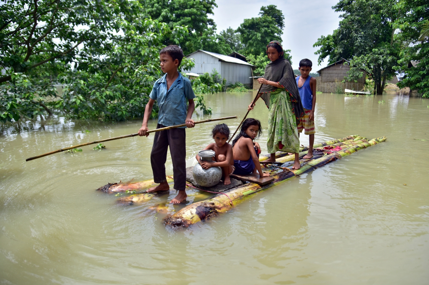 A family crossing floodwater on a bamboo raft