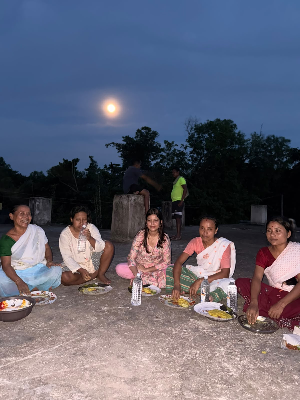 Community members receiving an evening meal outdoors